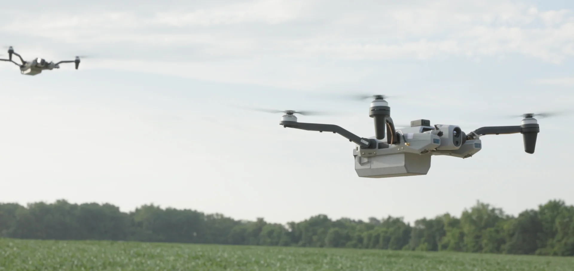 Two drones operating together over an open field